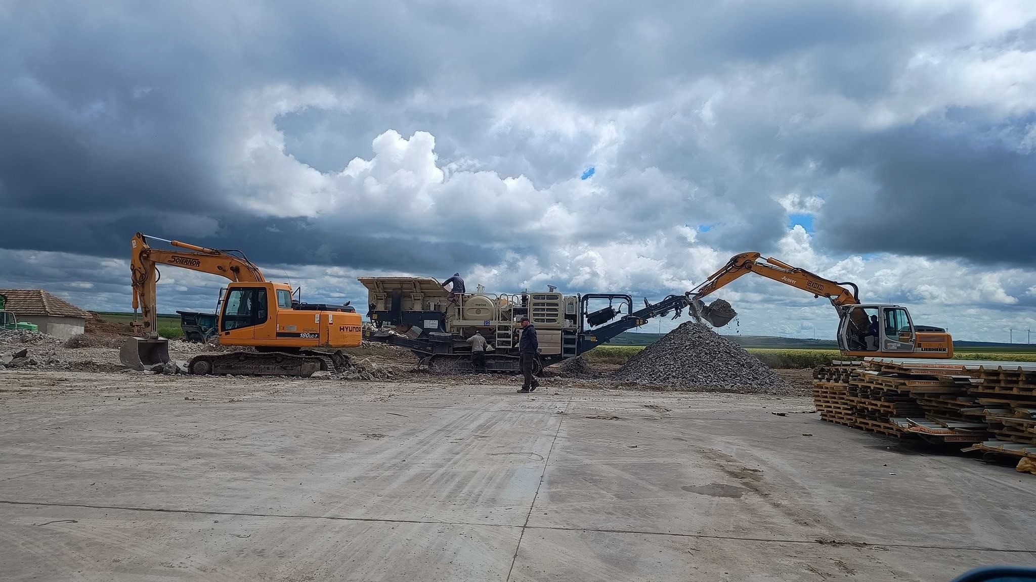 Concasor mobil și două excavatoare la reciclarea betonului